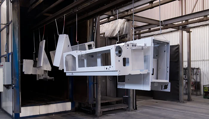 Steel components hanging in front of the powder coating curing oven.